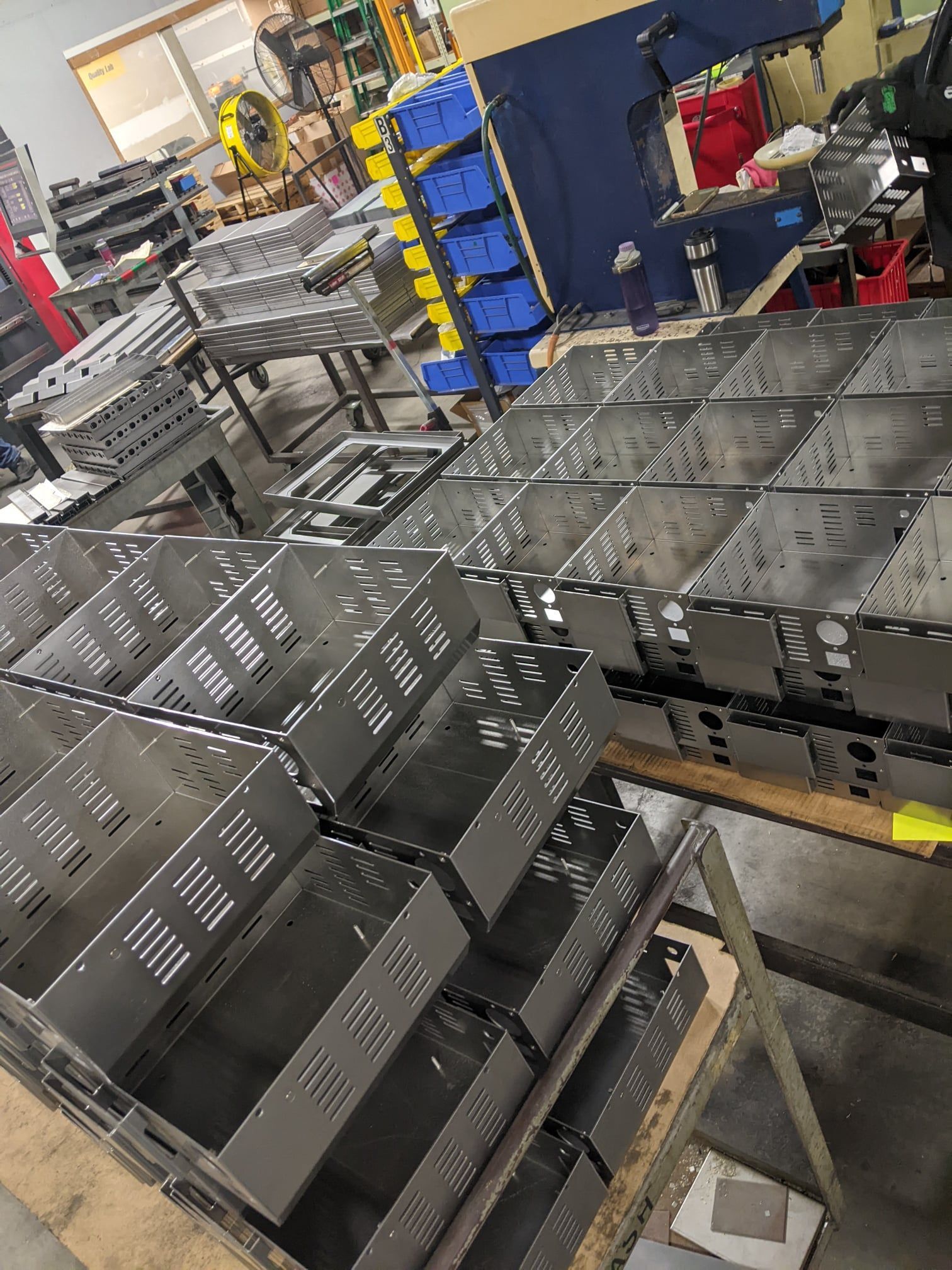 Rows of metal boxes stacked in a workshop, likely for assembly or storage.