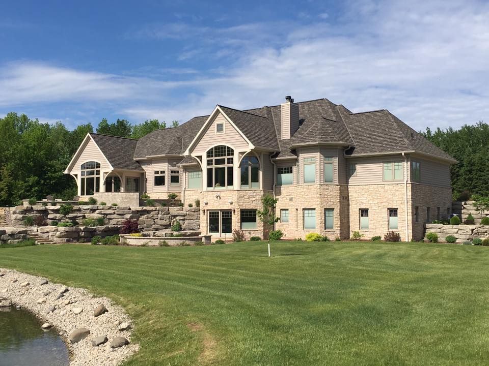 A large house with a lot of windows and a pond in front of it.