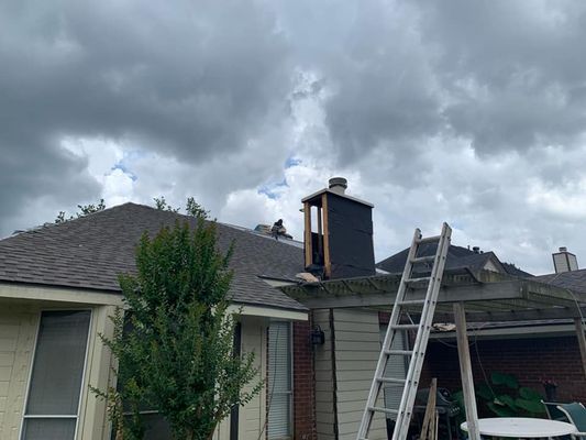Chimney repair on a cloudy day; a ladder rests against the side of the house near the chimney. The chimney is partially dismantled.