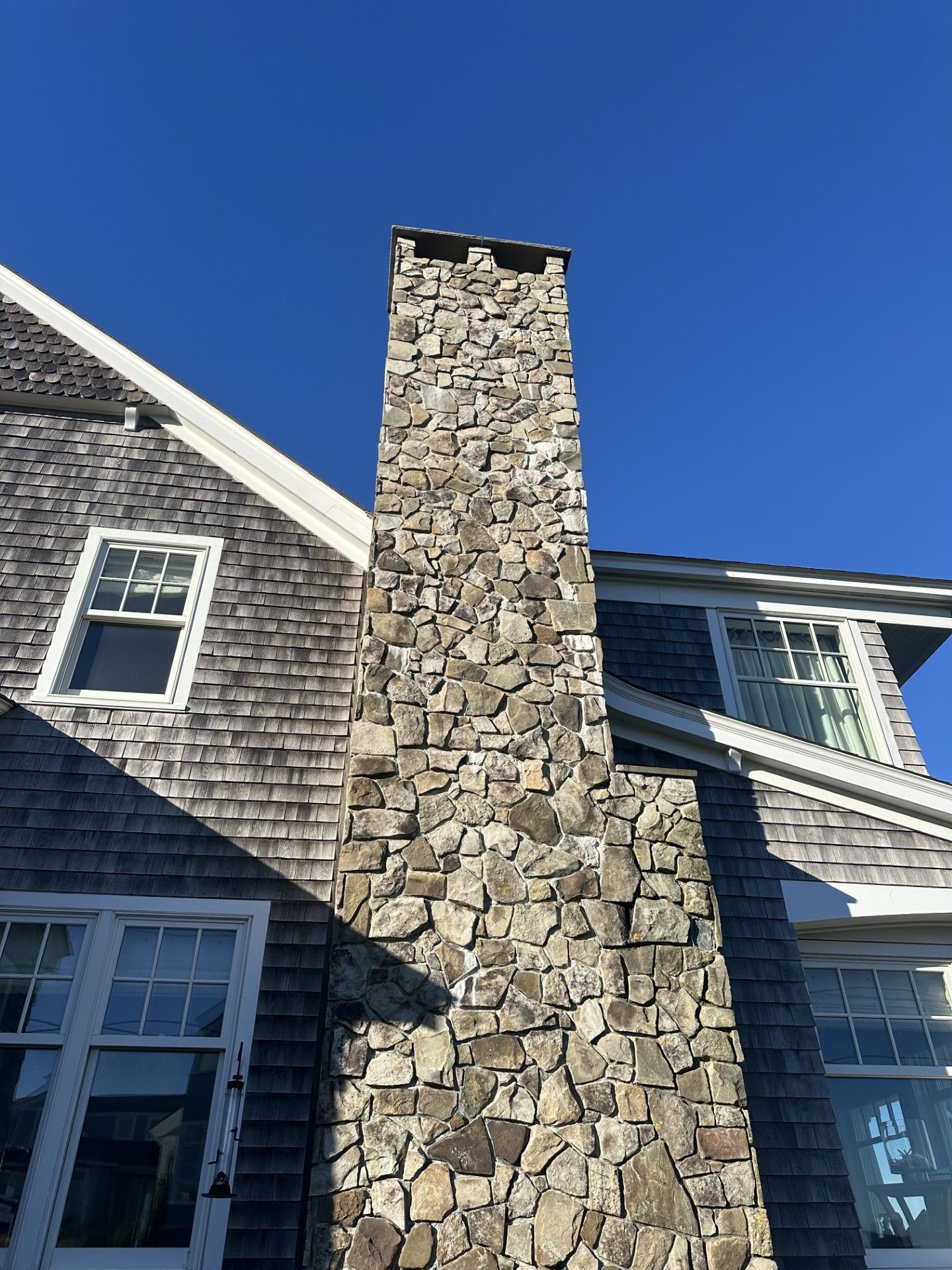 A large stone chimney is on the side of a house.