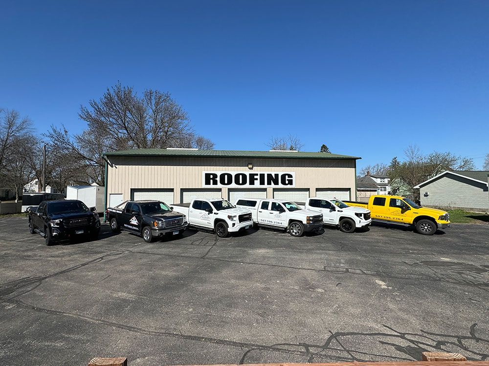 A row of trucks parked in front of a building that says roofing