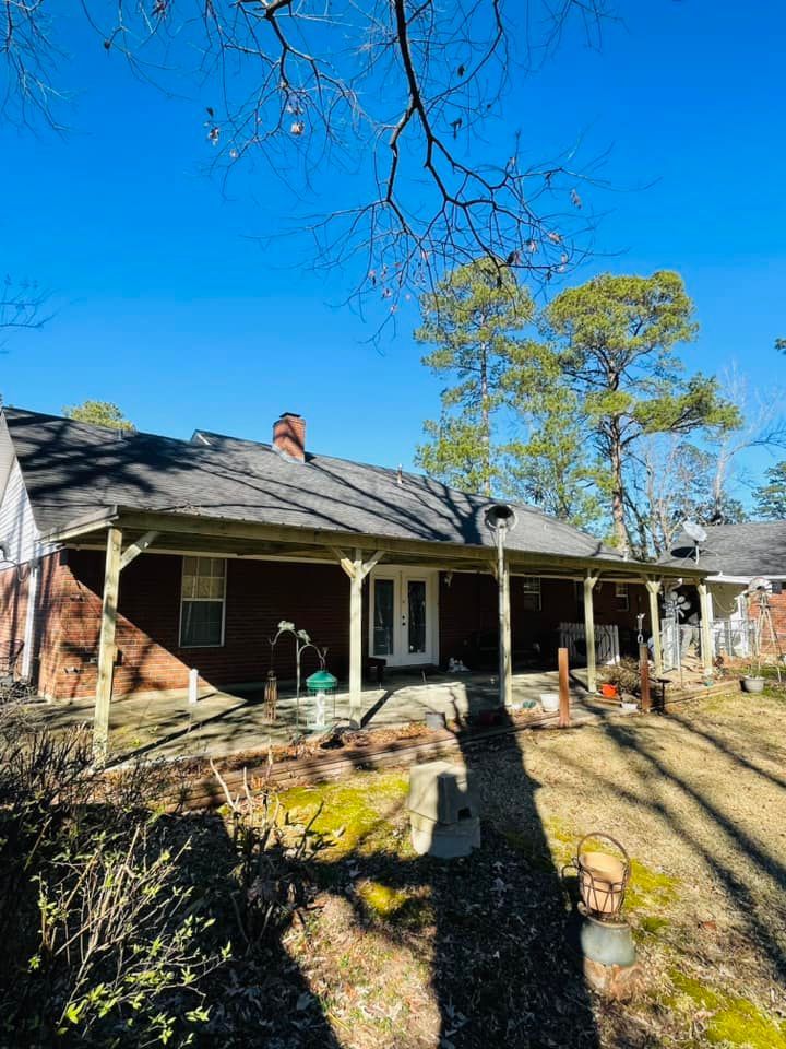 A brick house with a porch and a chimney on the roof.