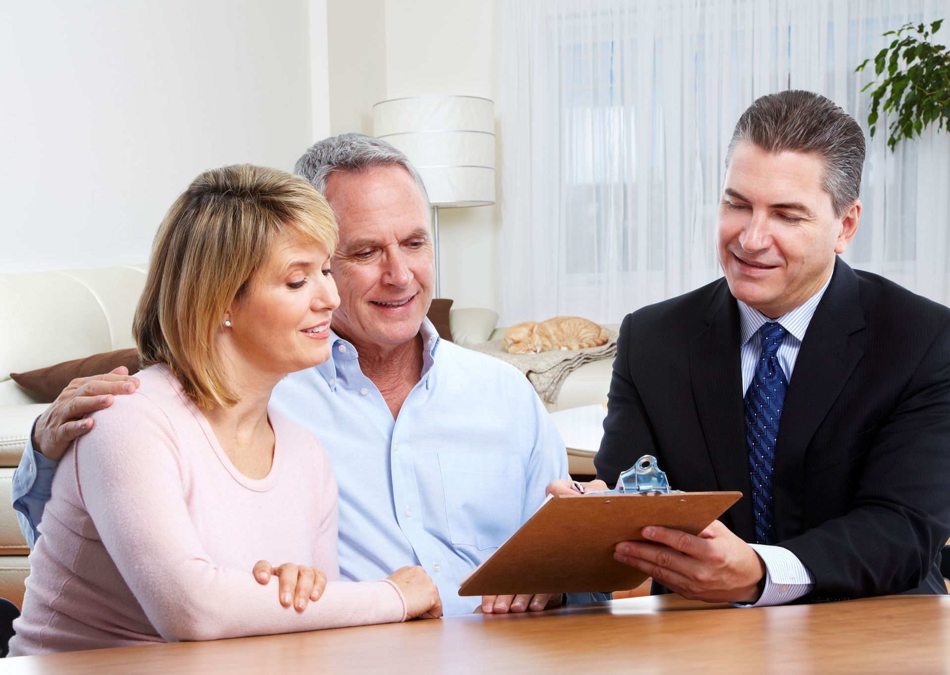 Three people reviewing paperwork together at a table in a bright office