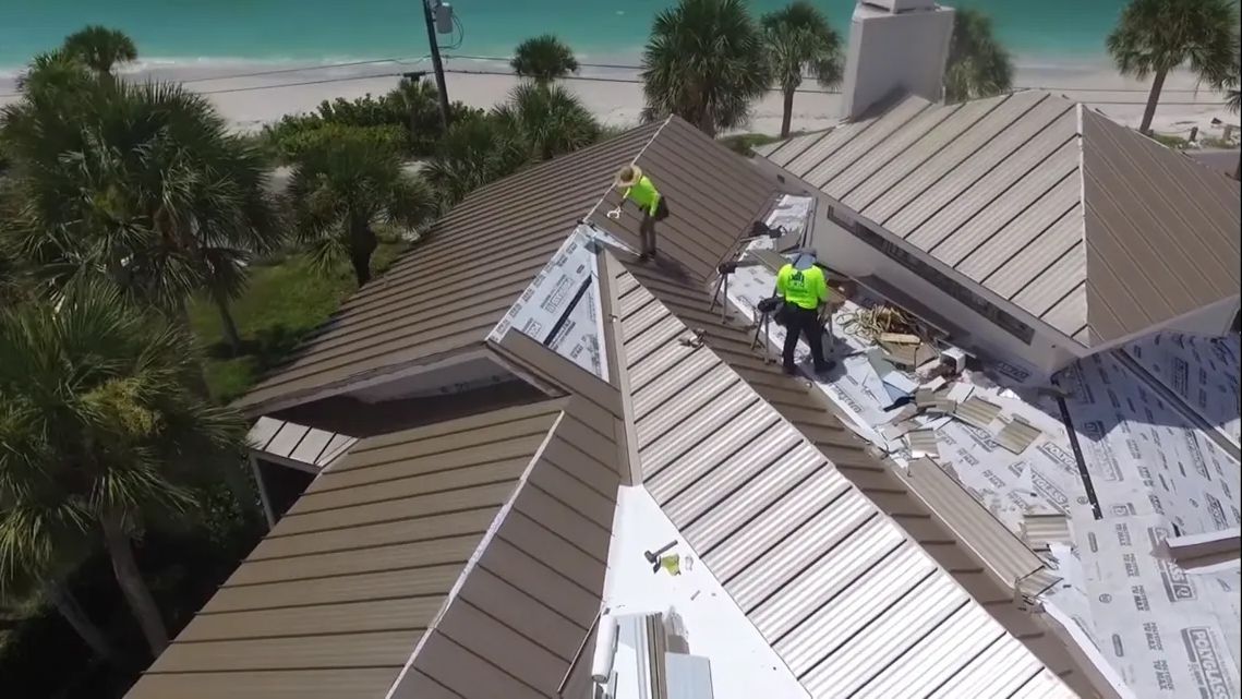 A couple of men are working on the roof of a house.