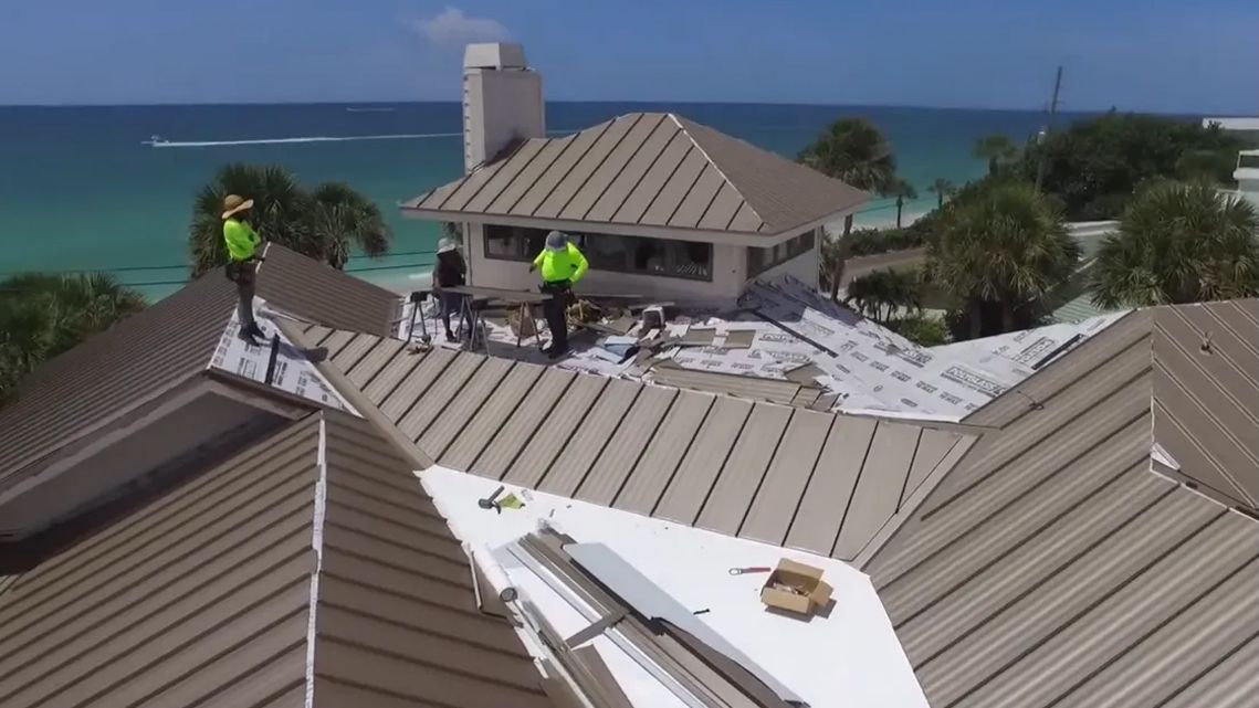 A group of men are working on the roof of a house.