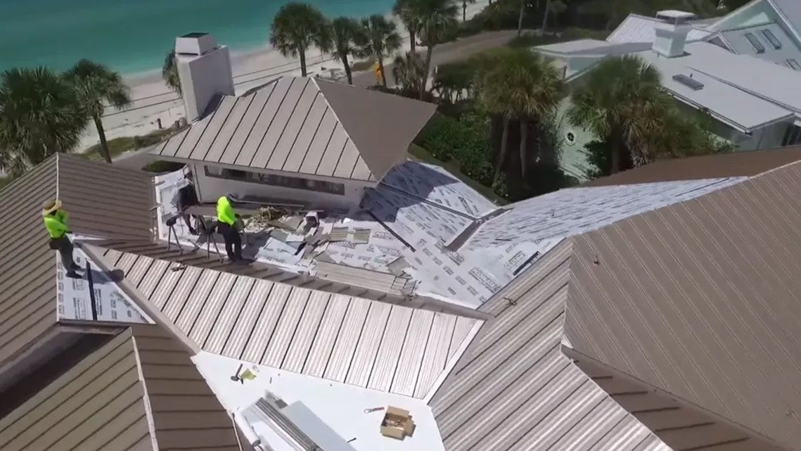 A group of men are working on the roof of a house.