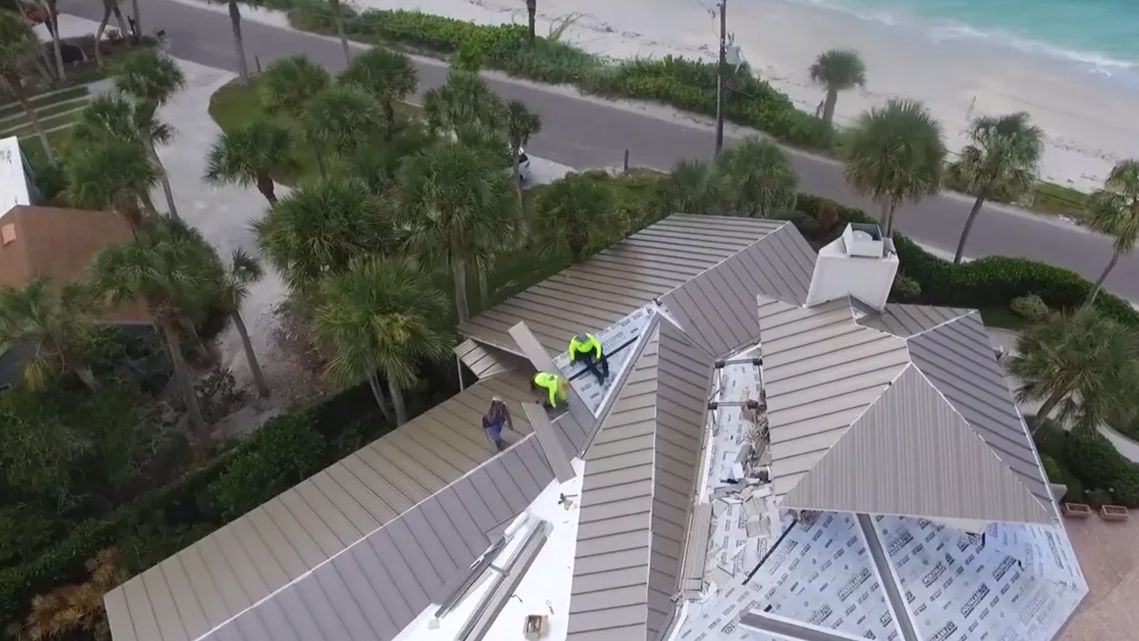 A group of men are working on the roof of a house.