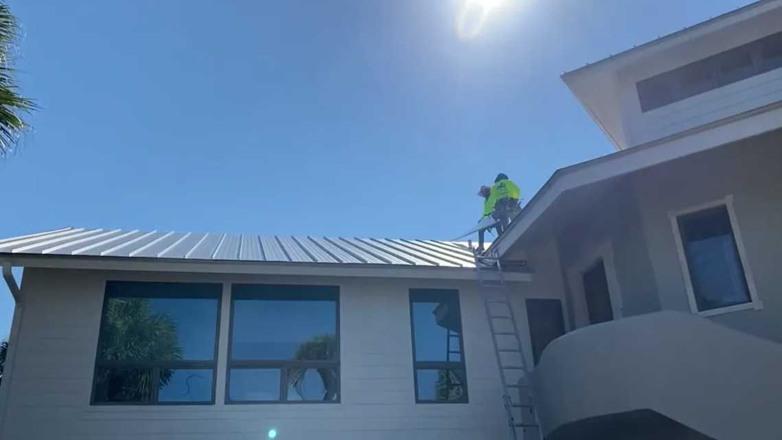 Two men are working on the roof of a house.