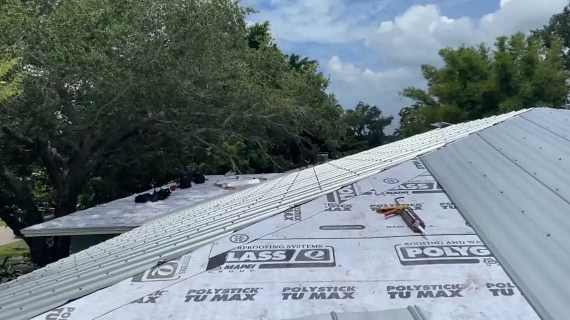 A roof with a lot of shingles on it and trees in the background.
