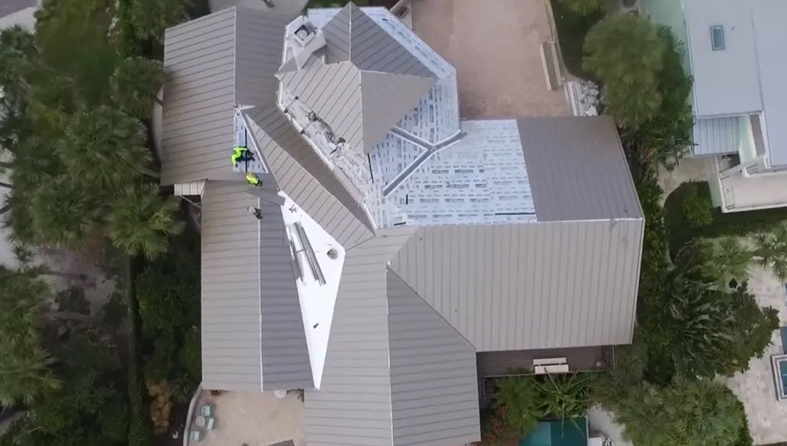 An aerial view of a large house with a roof being installed.