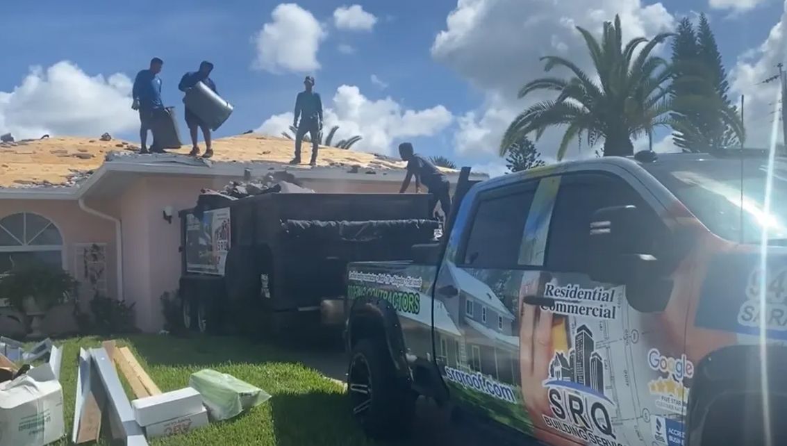 A group of men are working on the roof of a house.