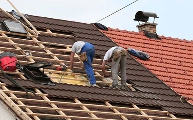 Two men are working on the roof of a house