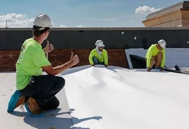 A group of construction workers are working on a roof.