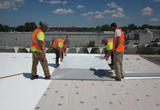 A group of men are working on a white roof