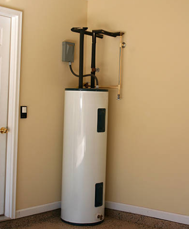 White water heater in a corner of a room with beige walls, pipes, and electrical box.