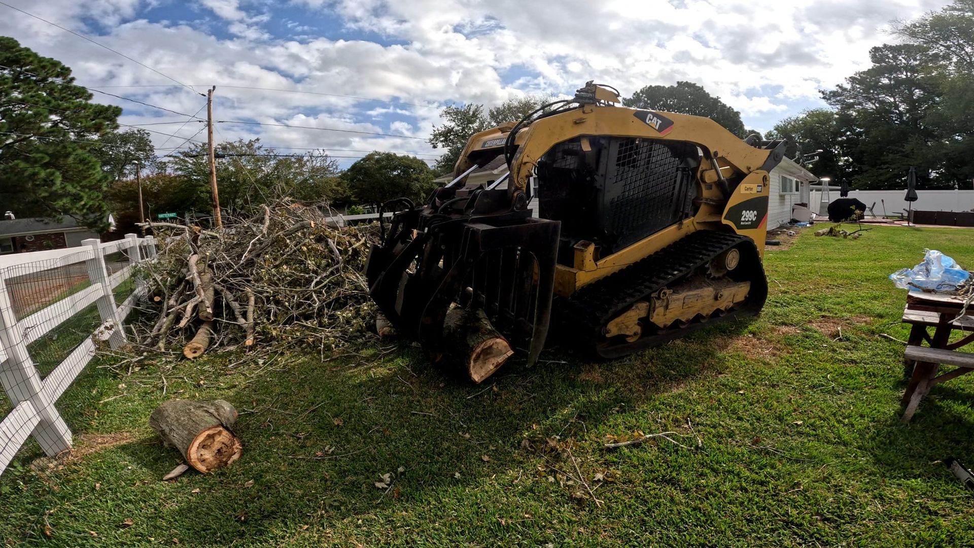 a bulldozer is cutting down a tree in a yard