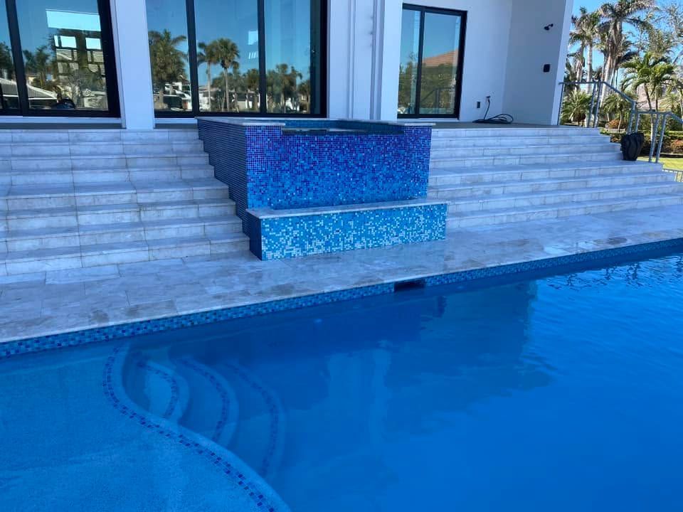 Blue-tiled pool with steps and a modern house patio in the background
