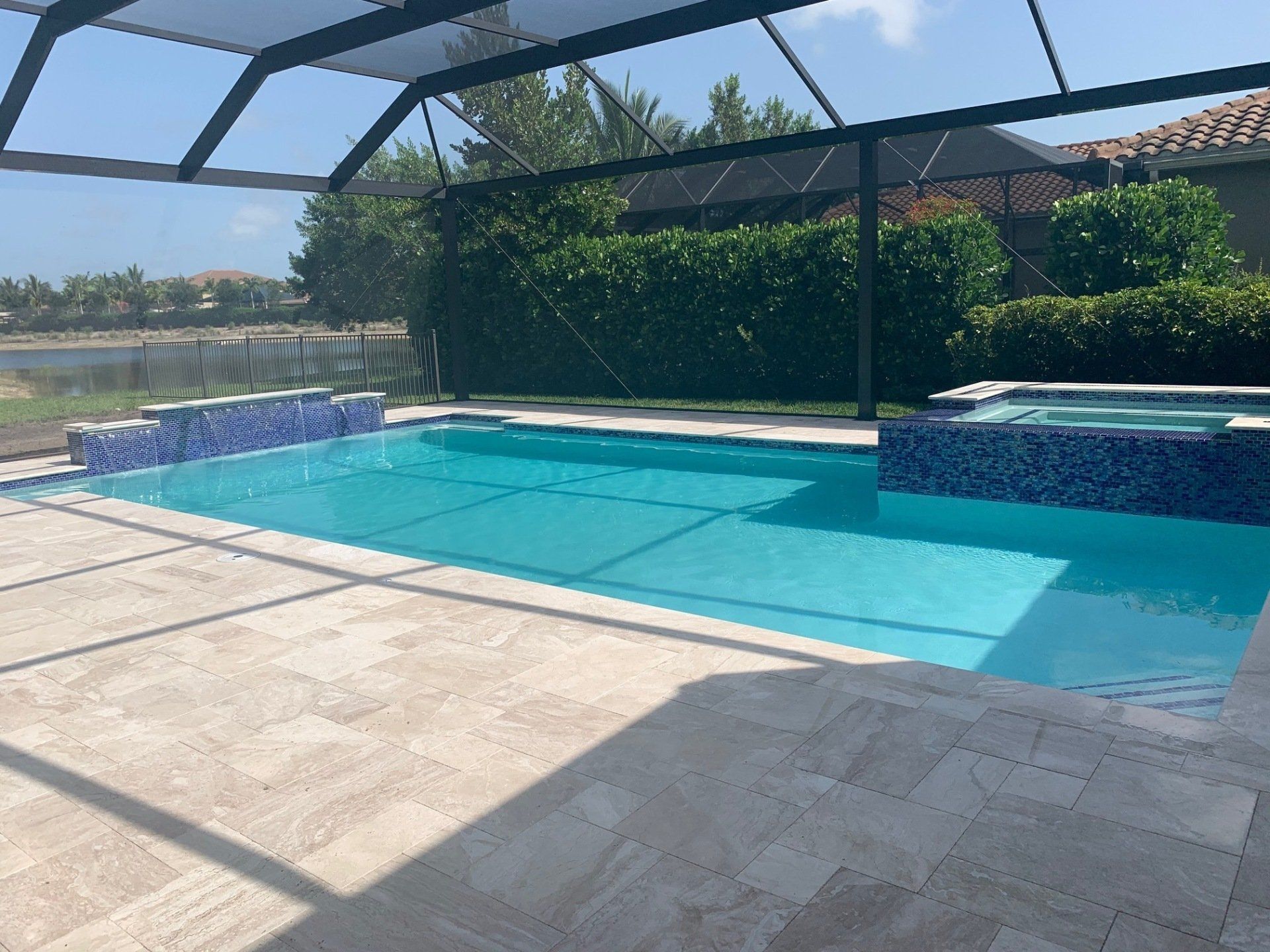 Sunlit backyard pool with blue water, stone patio, and screened enclosure