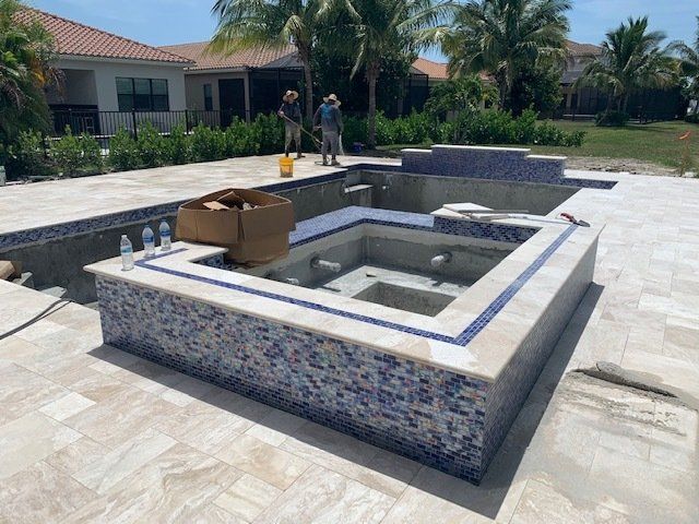 Backyard pool with raised spa, tile edging, and a worker setting materials nearby