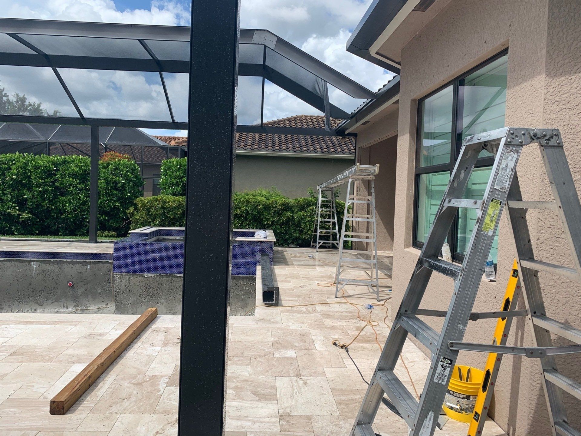 Patio under construction with ladders, beams, and tools beside a house.
