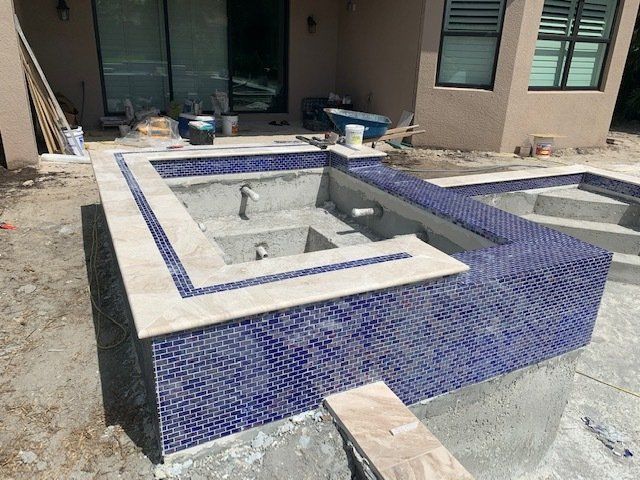 Blue tiled empty fountain pool under construction beside a building