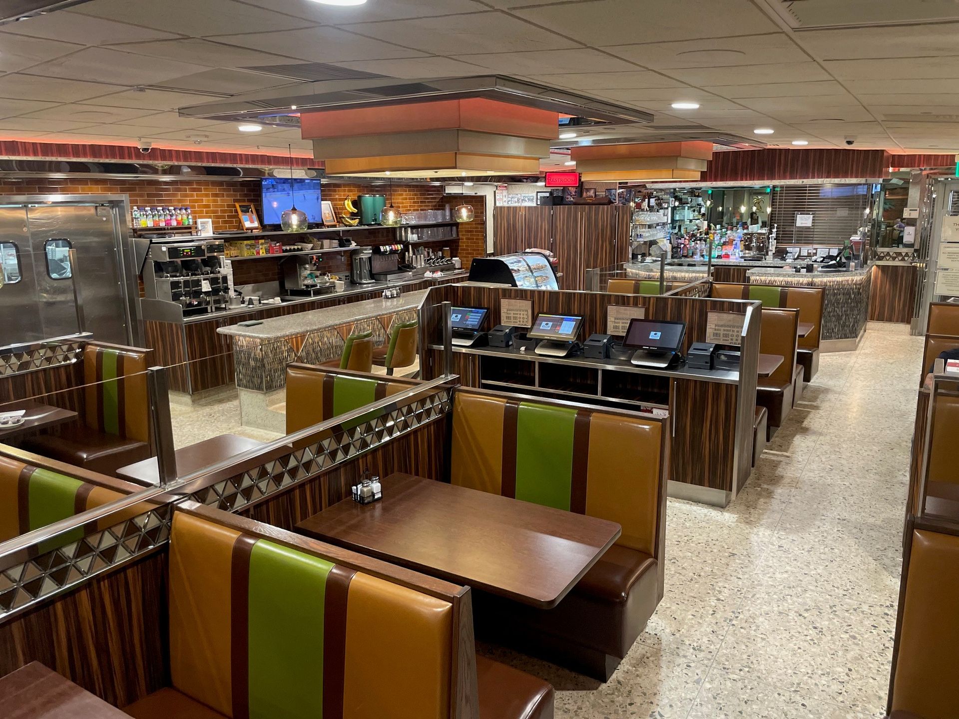 A diner with tables and booths and a kitchen in the background.
