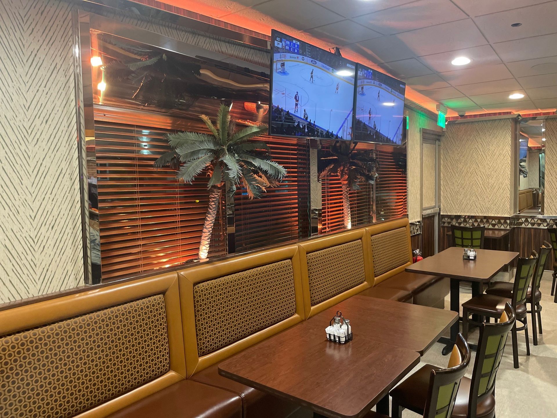 A restaurant with tables and chairs and a television on the wall.