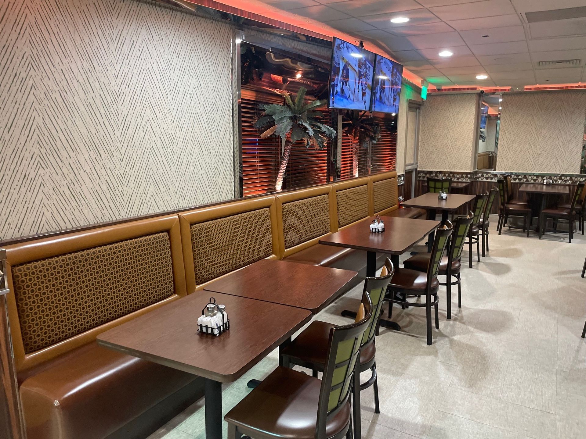 A restaurant with tables and chairs and a television on the wall.