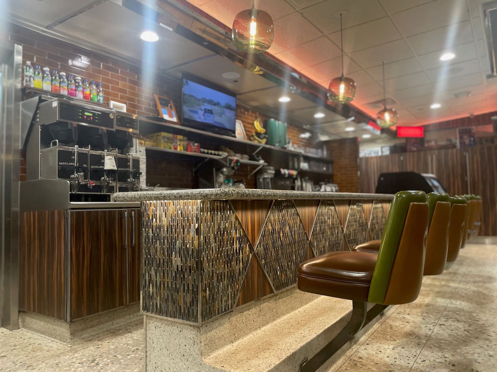 A diner with a bar and chairs and a television on the wall.
