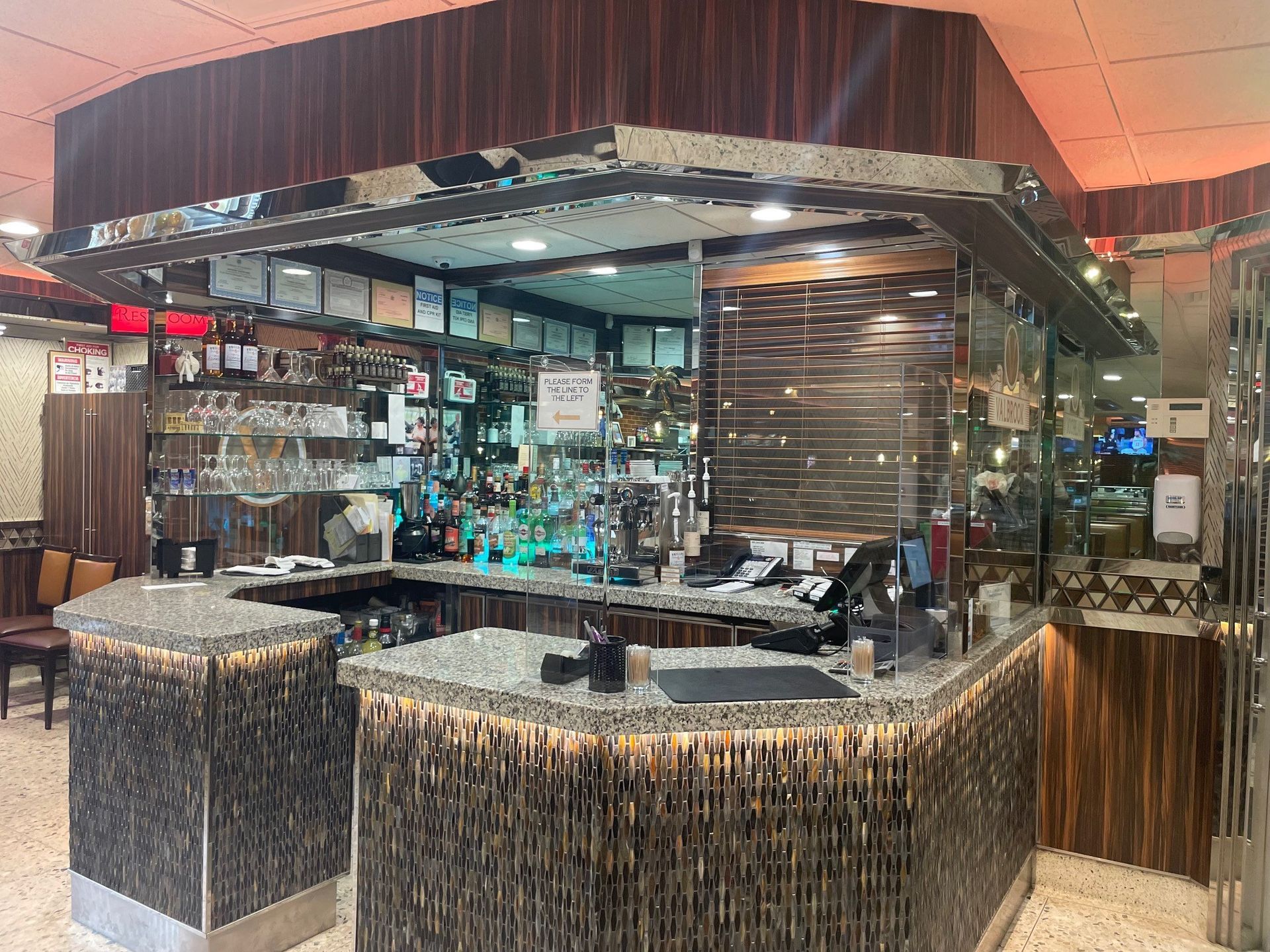 A restaurant with a bar and a counter in the middle of the room.