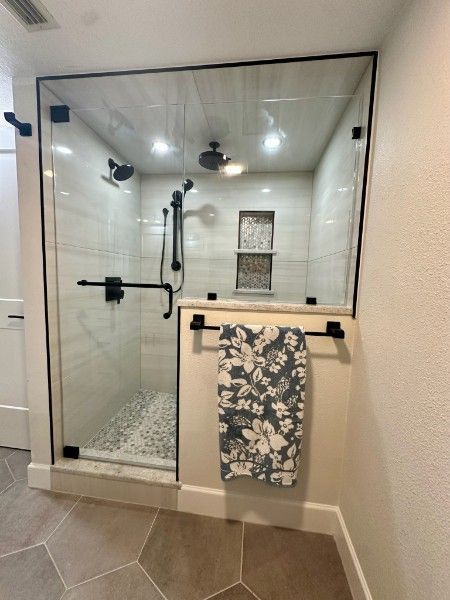 A bathroom with a walk in shower and a towel hanging on the wall
