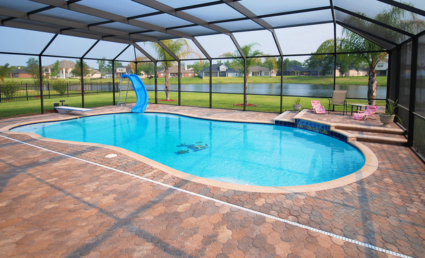 A large swimming pool is surrounded by a screened in area.