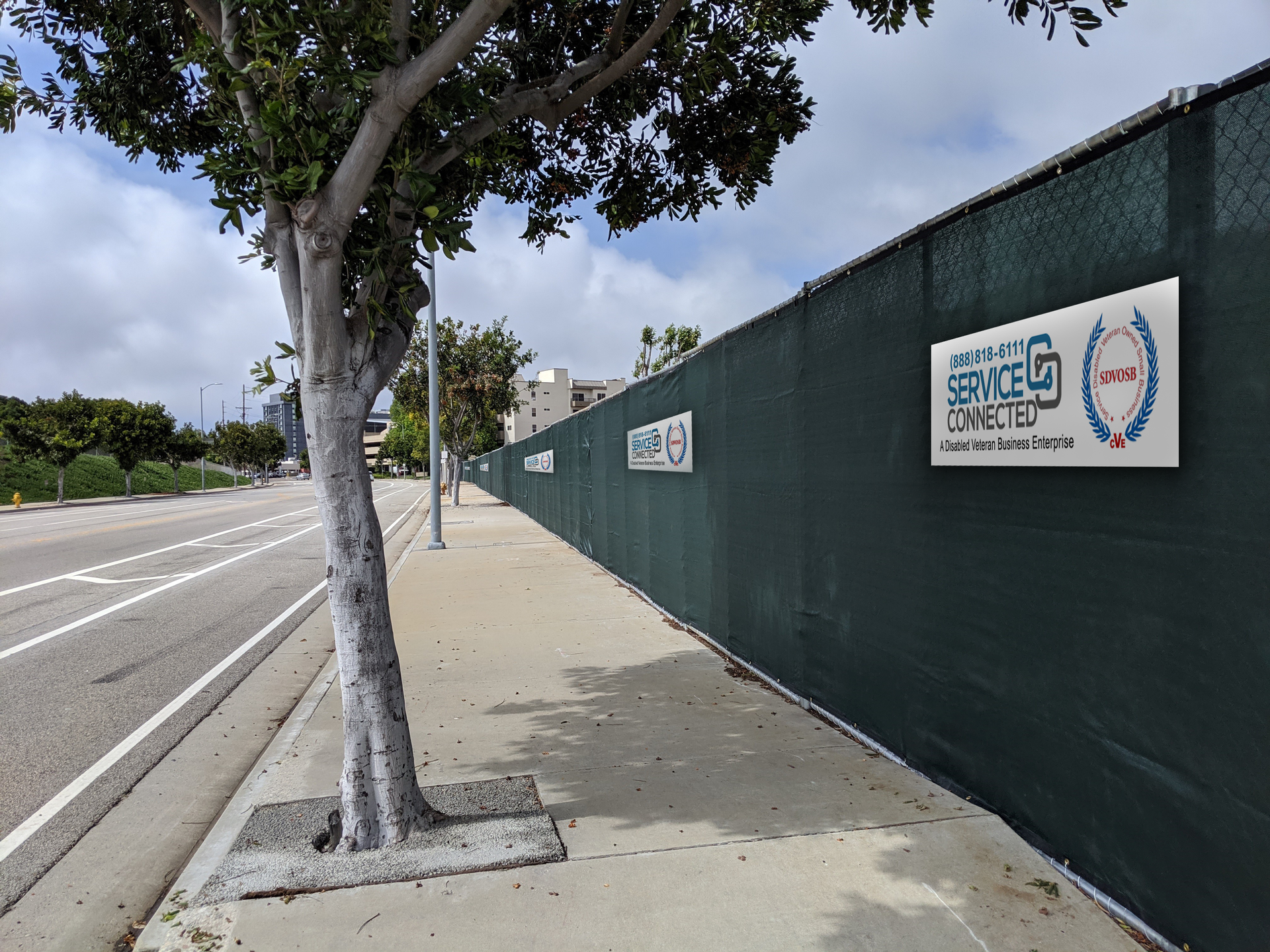 A sidewalk alongside a green fence