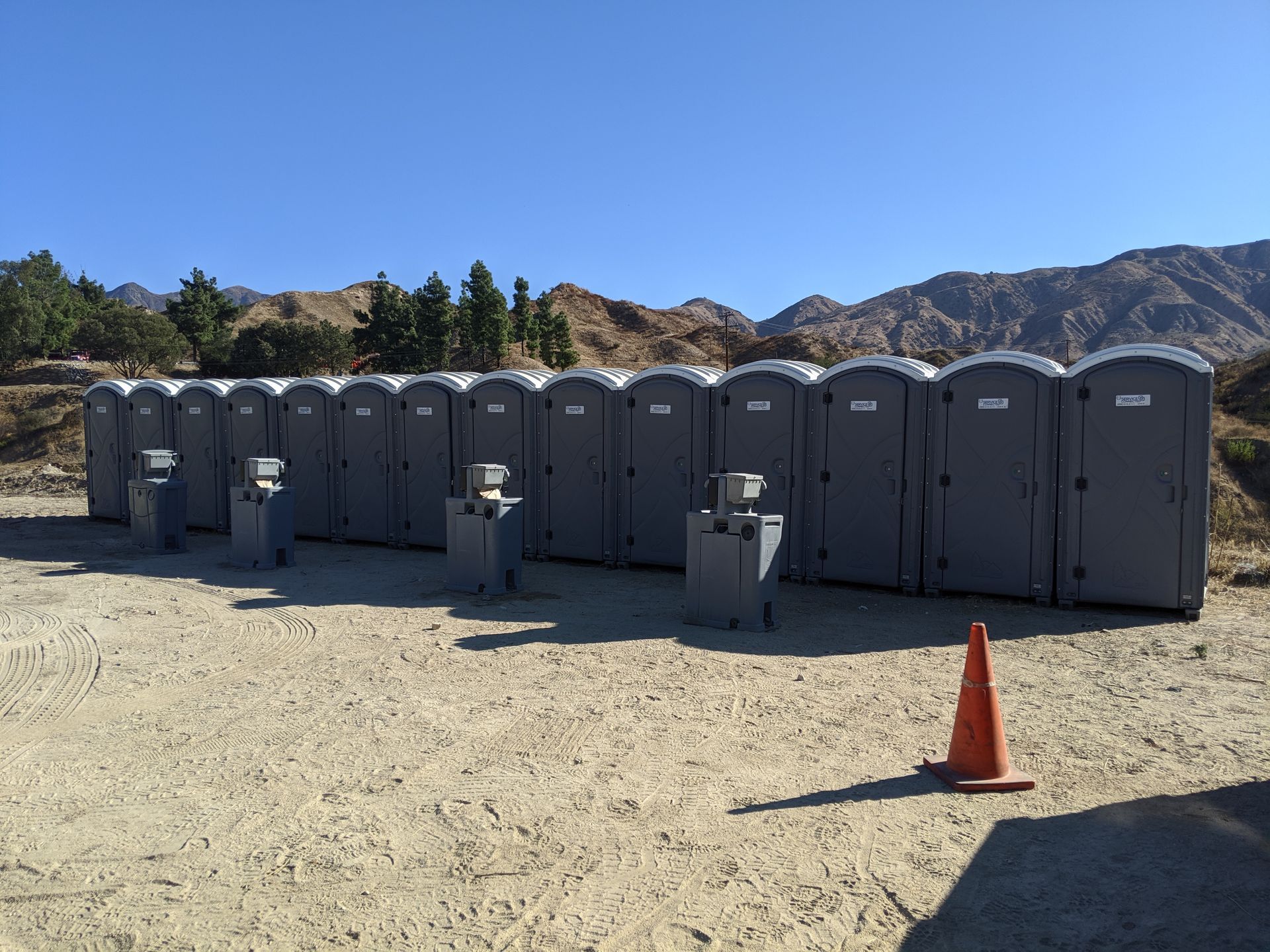 A row of gray portable toilets lined up outdoors
