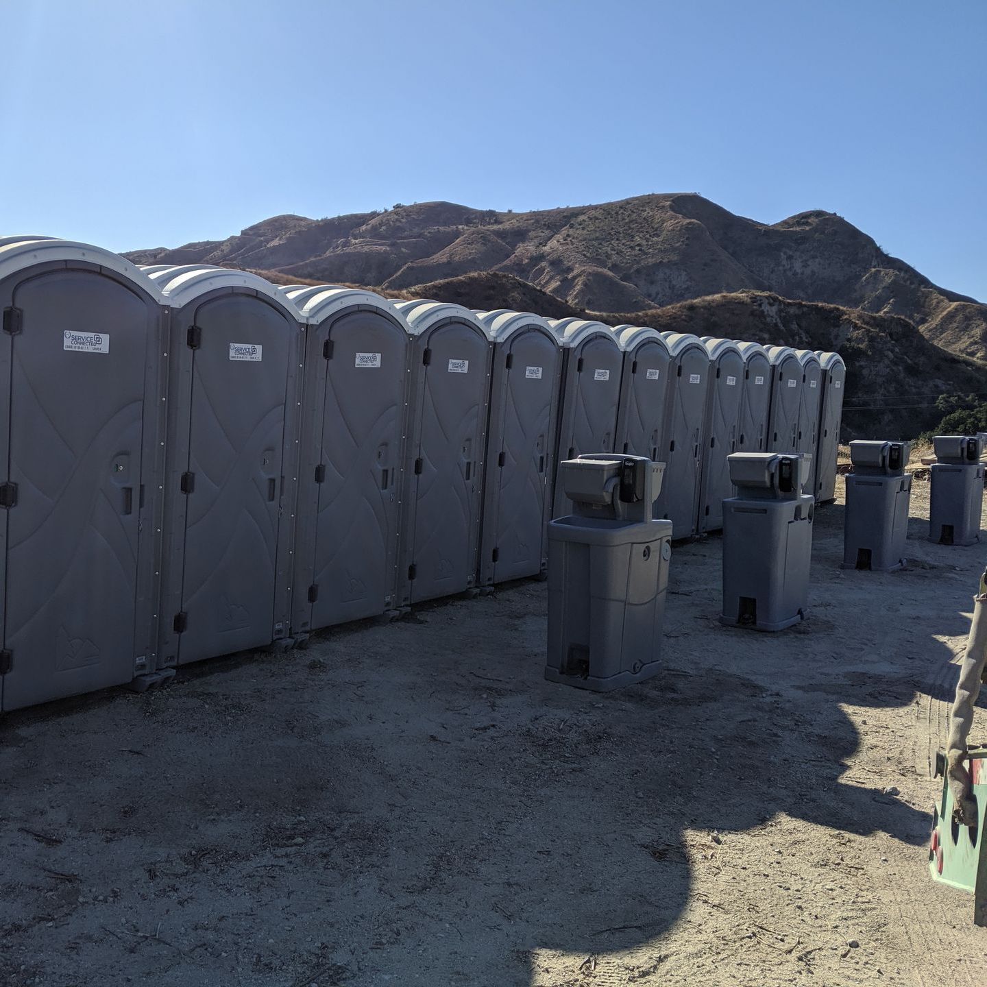 A row of gray portable toilets lined up outdoors