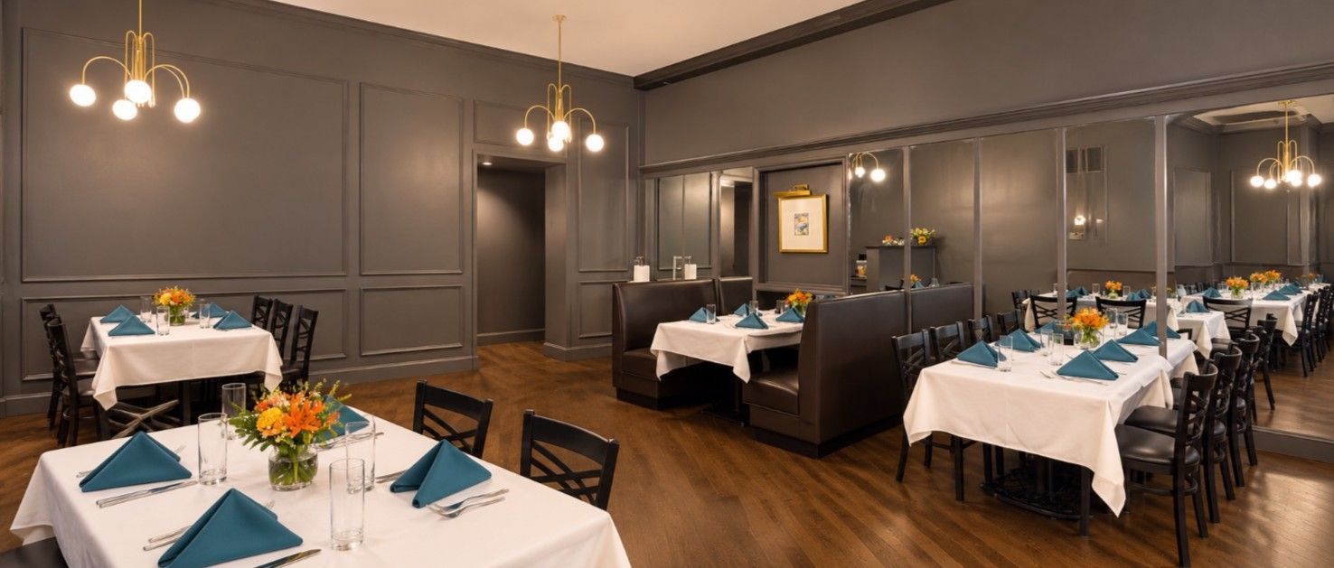 Elegant dining room set for a formal meal with white tablecloths and gray walls