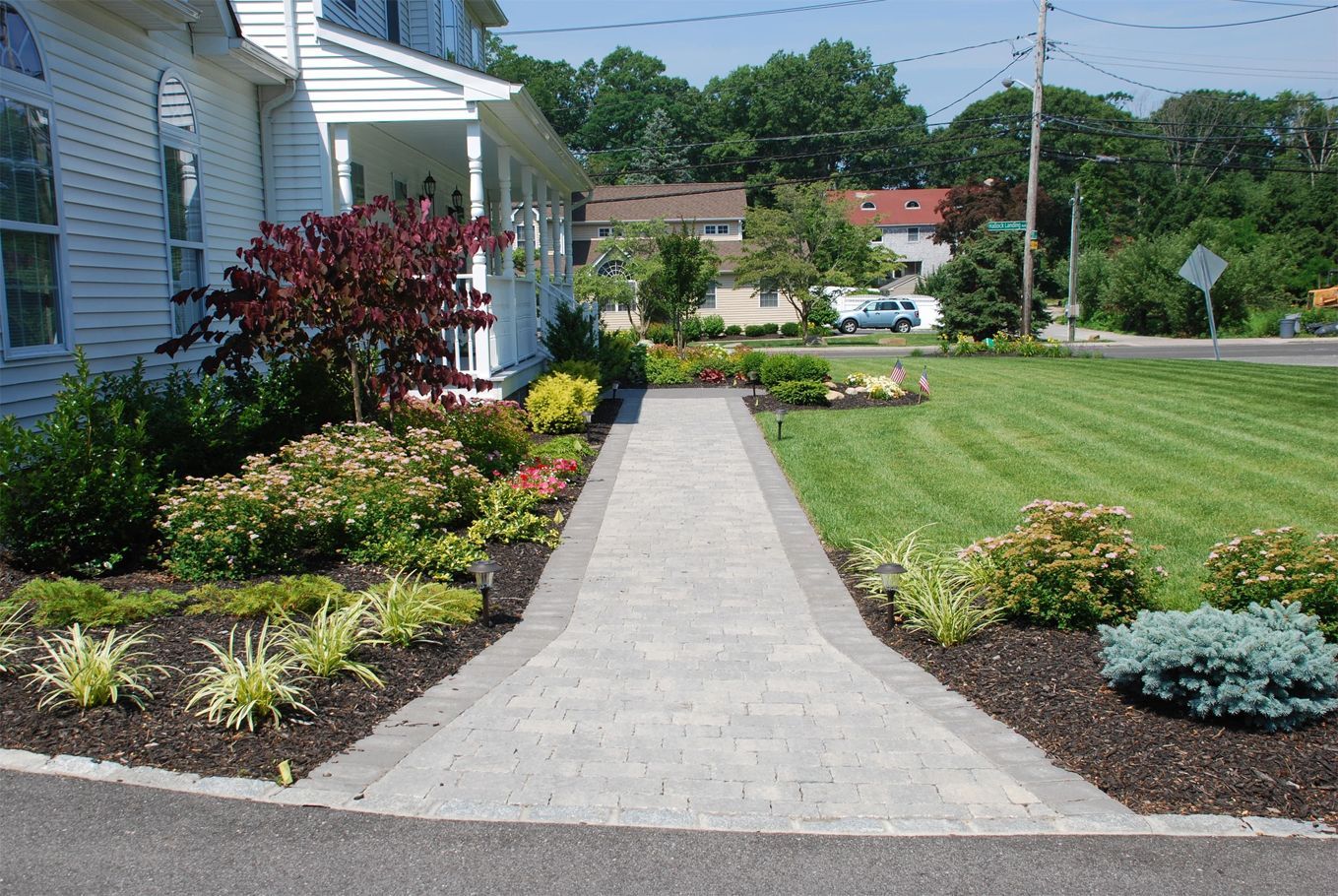 A walkway leading to a house with a lush green lawn