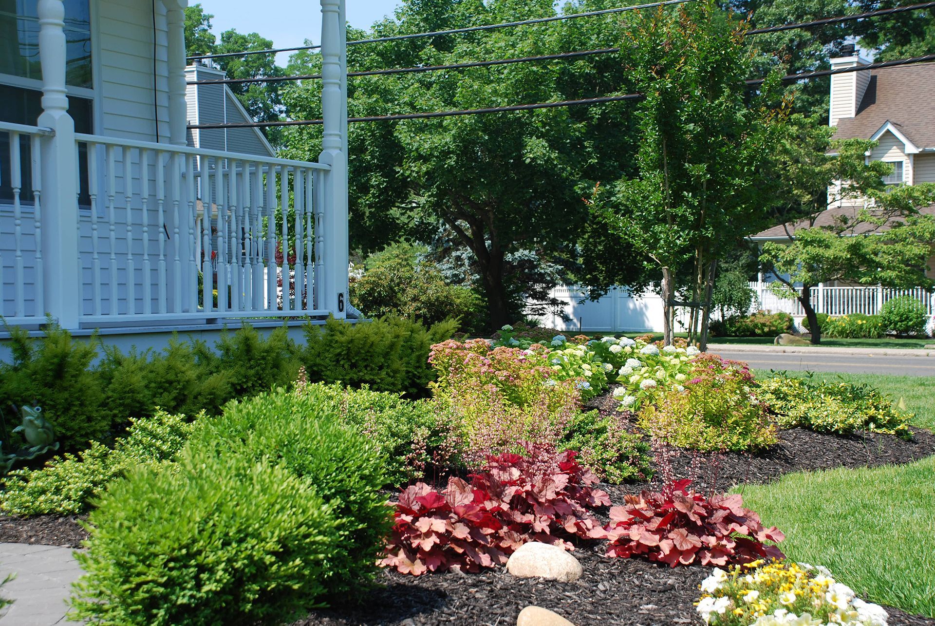 A white house with a porch and a garden in front of it
