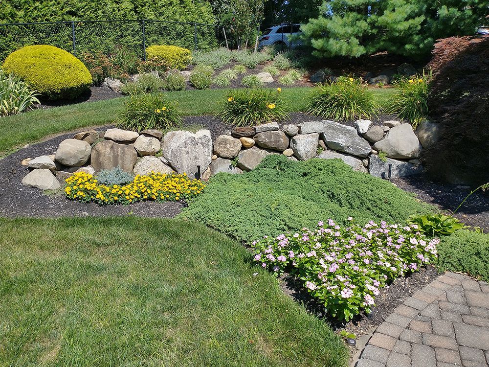 A garden with flowers and rocks and a brick walkway