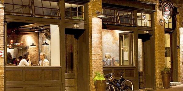A group of people are sitting at a table outside of a restaurant.