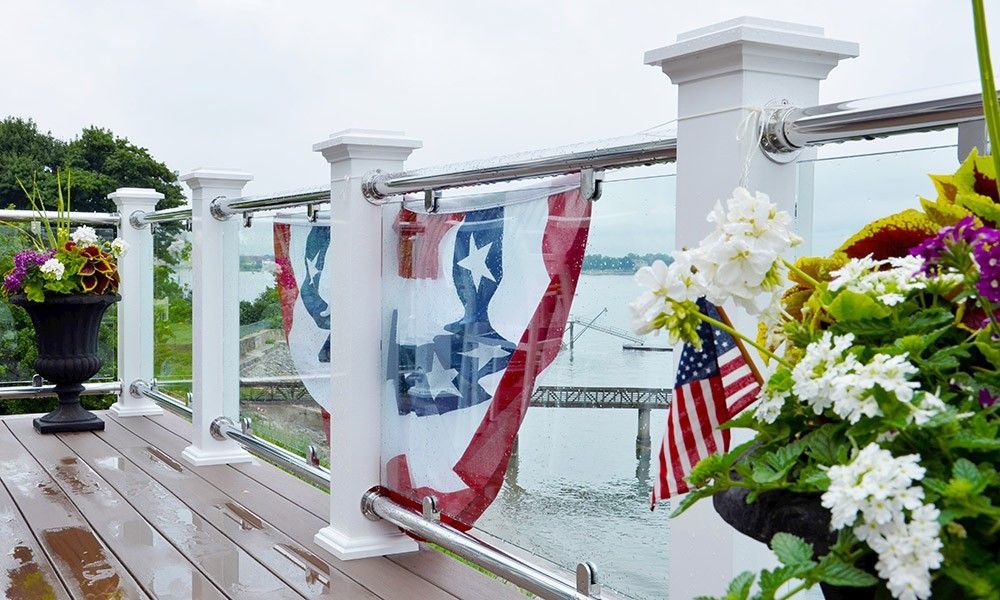 A deck with flowers and flags on it and a view of the water.