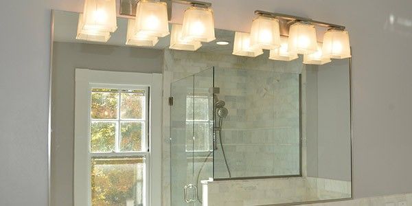 A bathroom mirror with lights above it and a window.