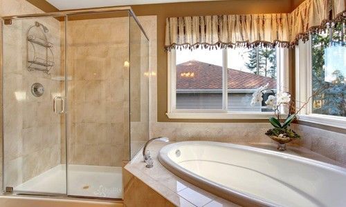 A bathroom with a tub , shower , and window.
