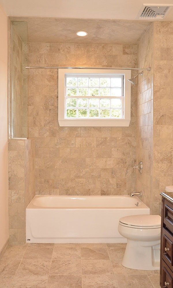 A bathroom with a tub , toilet , and window.