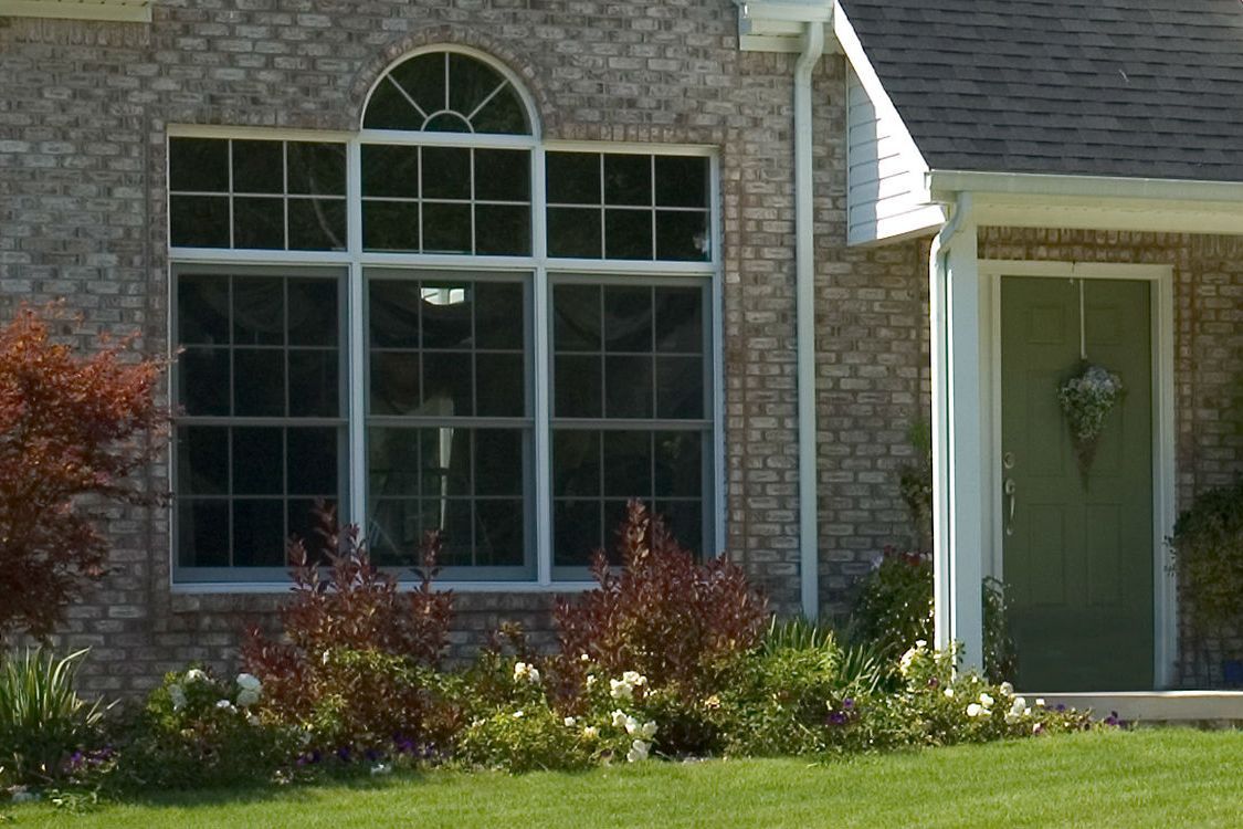 A brick house with a green door and a large window