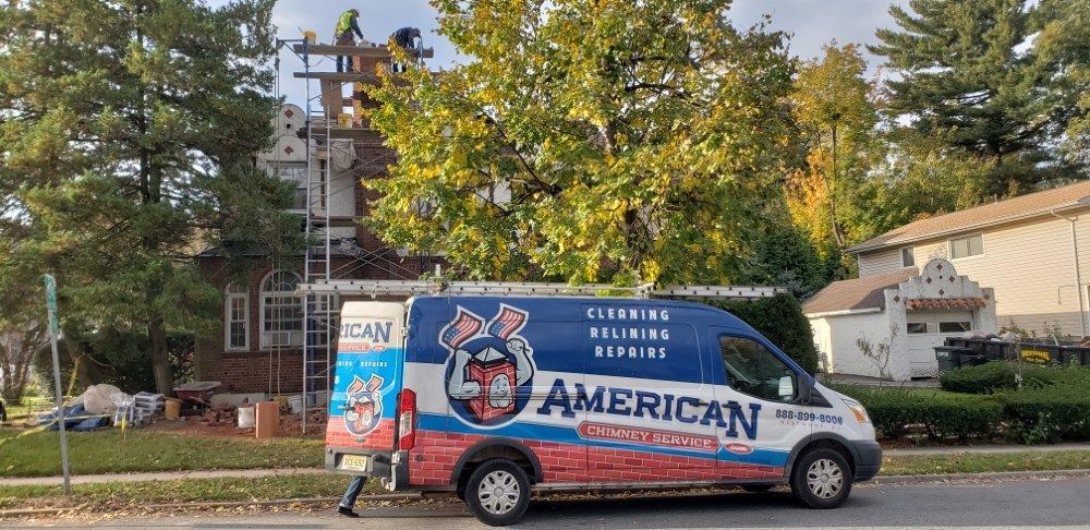 American chimney services van is parked on the side of the road in front of a house.
