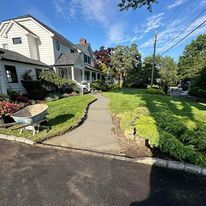 There is a wheelbarrow in the grass in front of a house.