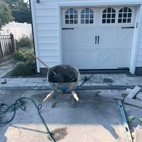 A wheelbarrow filled with concrete is sitting in front of a garage door.