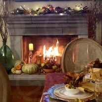 A table set for a thanksgiving dinner in front of a fireplace.