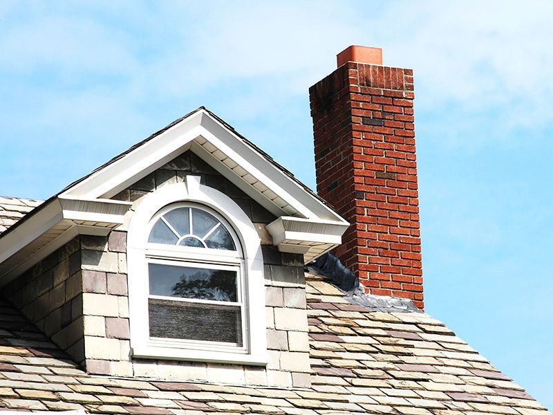A brick chimney is on the roof of a house